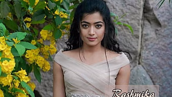 HD-wallpaper-rashmika-mandanna-is-wearing-white-dress-standing-near-yellow-flowers-tree-girls-thumbnail