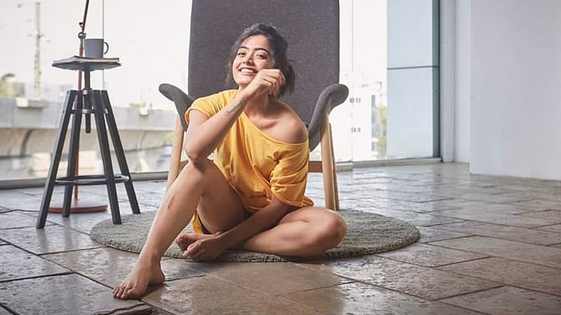 HD-wallpaper-smiley-rashmika-mandanna-is-wearing-yellow-dress-sitting-on-floor-in-chair-background-girls